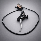 Sur-Ron Ultra Bee OEM hydraulic brake lever and caliper on gray background, complete front and rear brake upgrade kit for electric dirt bikes.